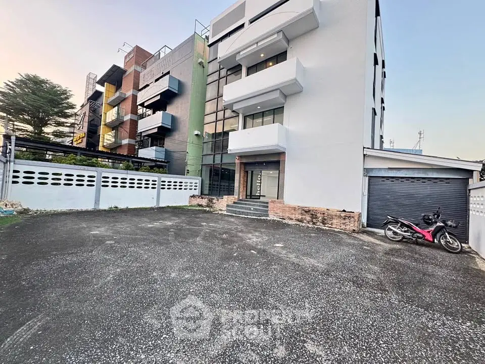 Modern multi-story building with spacious parking area and sleek design.