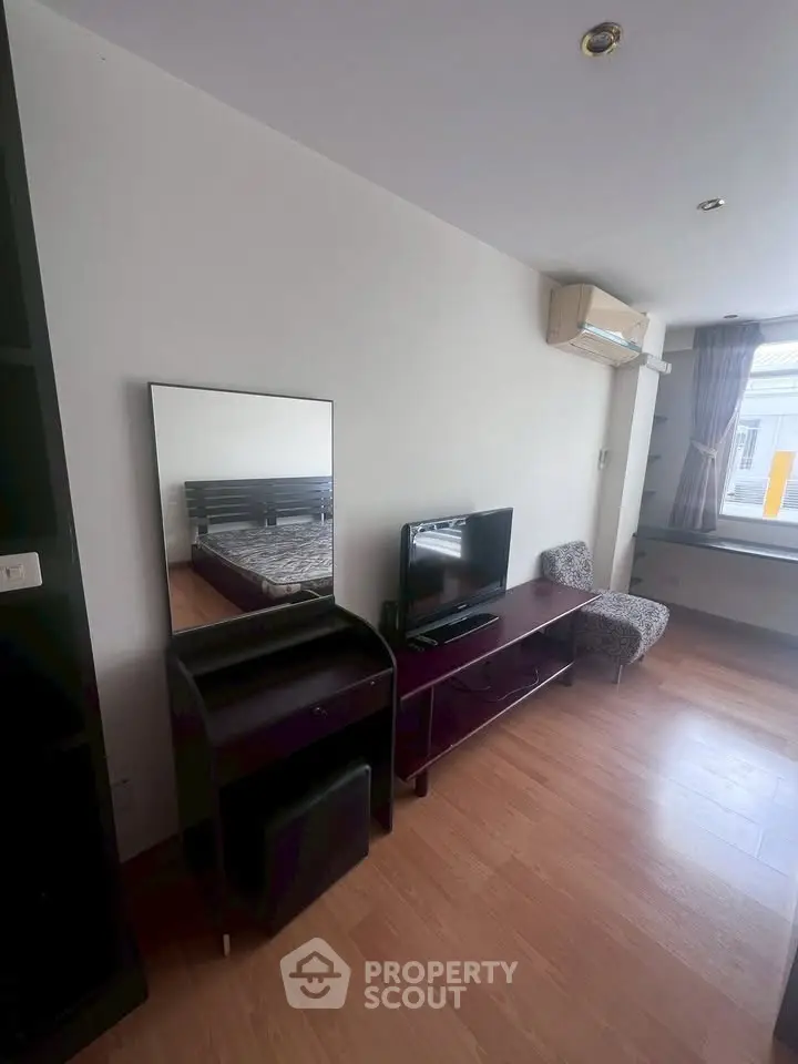 Cozy bedroom with modern furniture and natural light, featuring a TV and air conditioning.