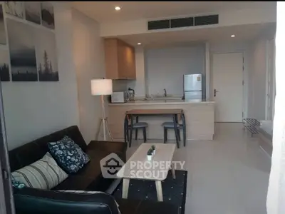 Modern open-layout living room and kitchen with sleek furniture and appliances.