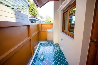 Charming small balcony with colorful tiles and wooden window frame, perfect for cozy outdoor relaxation.