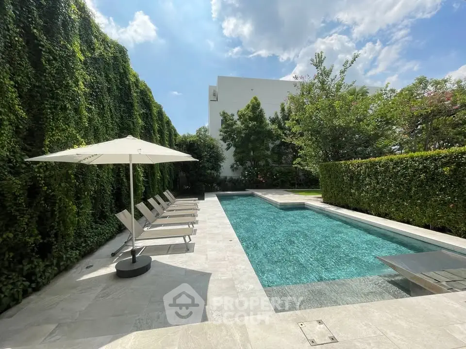 Luxurious private pool with sun loungers and lush greenery, perfect for relaxation and entertainment.