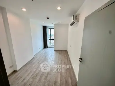 Spacious unfurnished room with large window and wooden flooring
