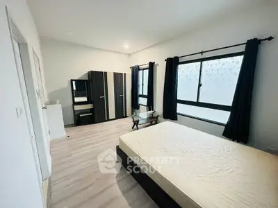 Spacious bedroom with modern furniture and large windows for natural light.