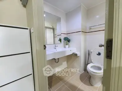 Modern bathroom with sleek fixtures and neutral tiles, featuring a large mirror and stylish plant decor.
