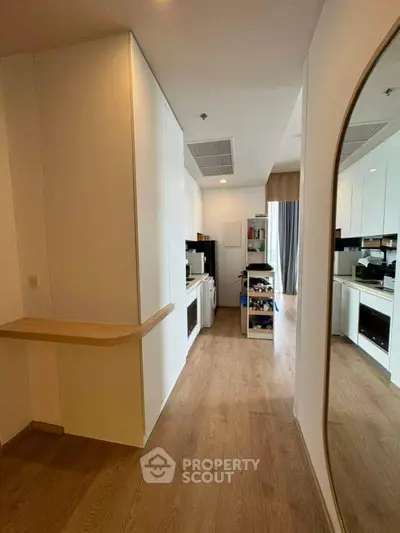 Modern kitchen with sleek cabinetry and wooden flooring in a stylish apartment.