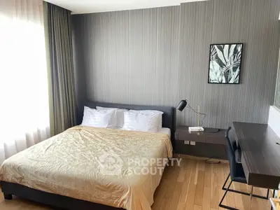 Modern bedroom with stylish decor and natural light, featuring a comfortable bed and sleek workspace.