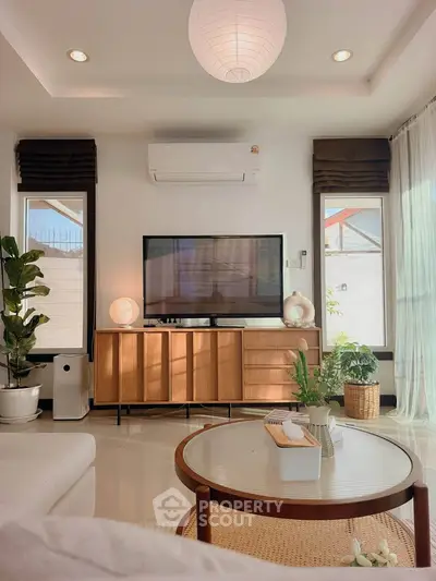 Stylish living room with modern decor and natural light, featuring a TV and elegant furniture.