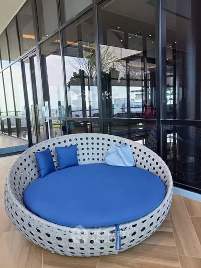 Luxurious outdoor seating on a modern balcony with stunning glass facade and ocean view.