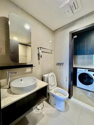 Modern bathroom with sleek fixtures and adjacent laundry area in a contemporary apartment.