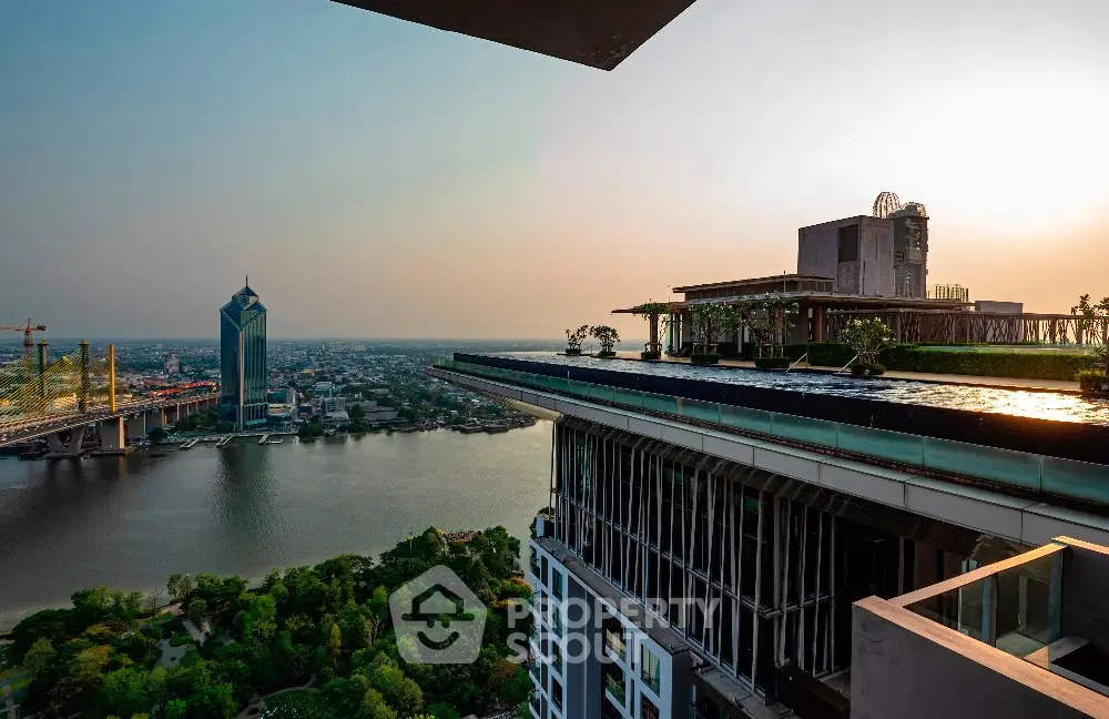 Stunning rooftop view with infinity pool overlooking river and cityscape at sunset.