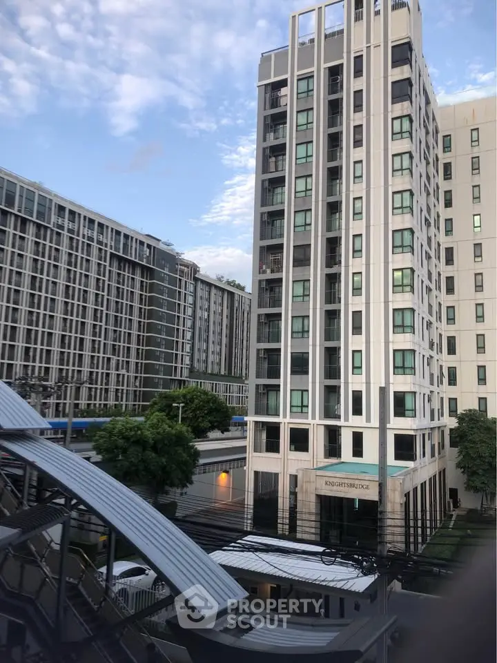 Modern high-rise apartment buildings with lush greenery and clear blue sky.