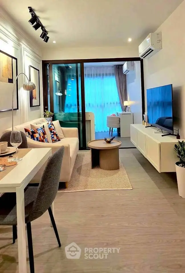 Modern living room with stylish decor and large TV, leading to a cozy balcony.