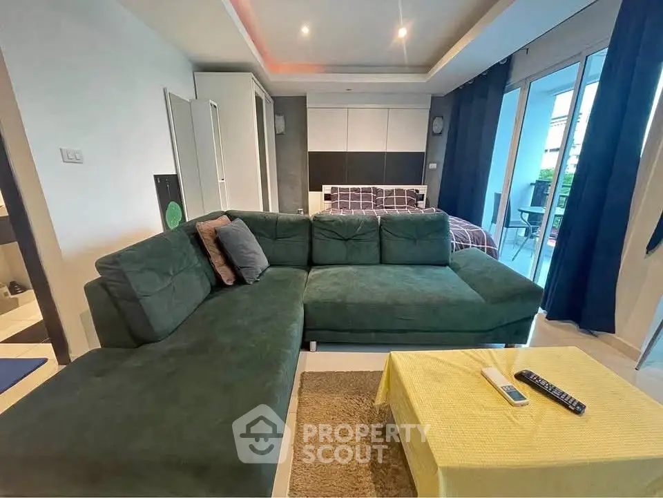 Stylish living room with modern green sofa and cozy bedroom view