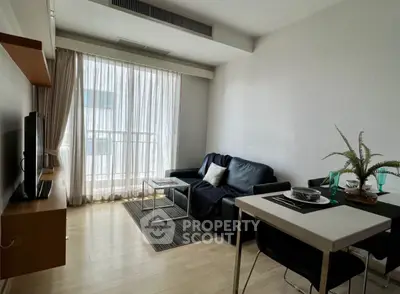 Modern living room with sleek furniture and natural light from large window.