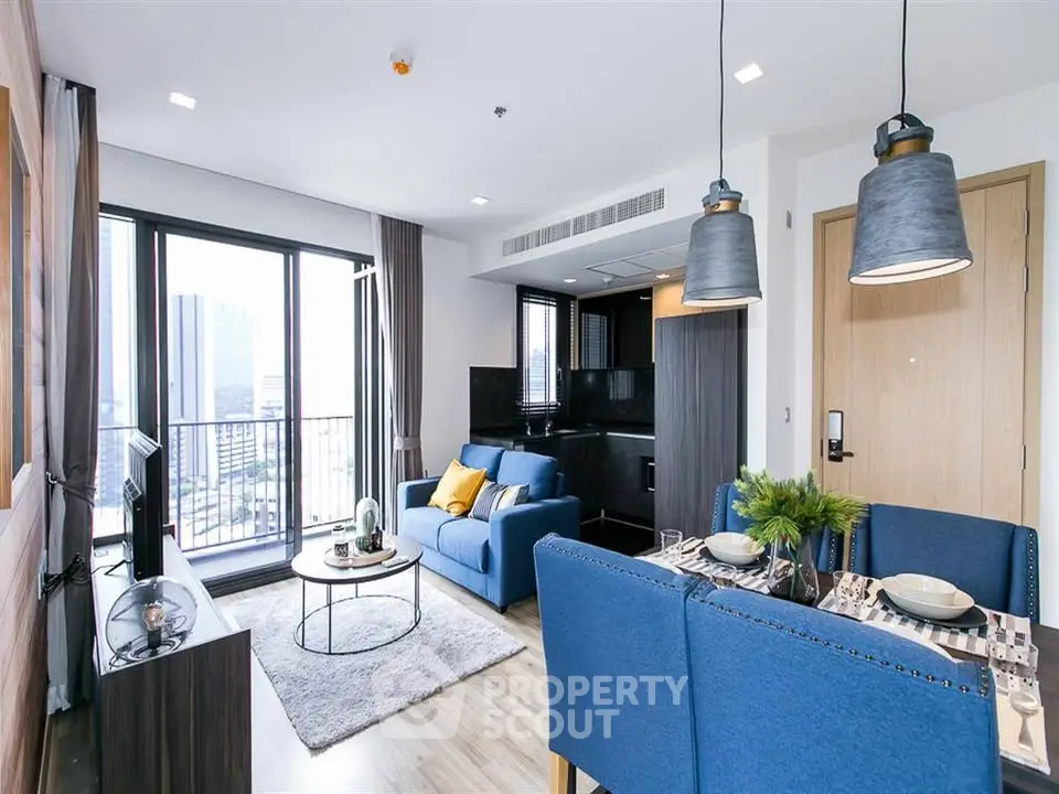 Modern living room with blue sofa and open kitchen in a high-rise apartment.