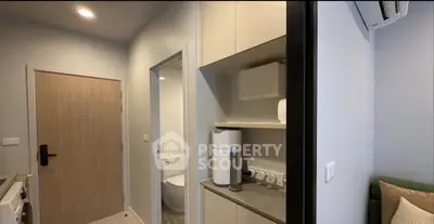 Modern apartment entryway with compact kitchen and bathroom access, featuring sleek design and efficient layout.