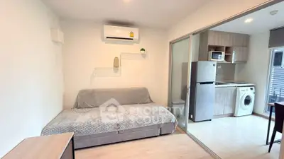 Modern living room with sofa, air conditioning, and adjacent kitchen featuring appliances.