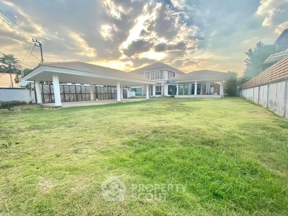 Spacious modern house with expansive green lawn and stunning sunset view, perfect for luxurious living.