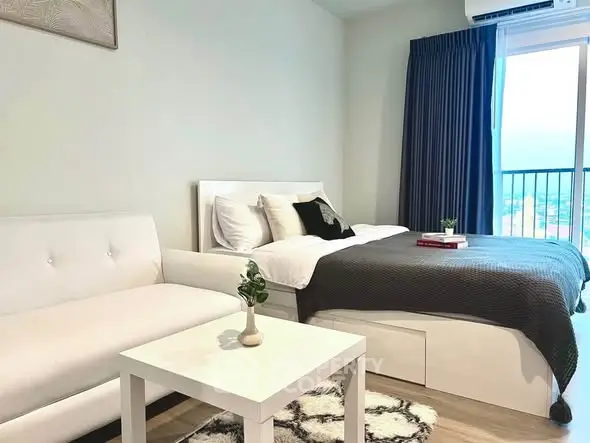 Modern bedroom with cozy decor and natural light, featuring a stylish sofa and elegant bedding.