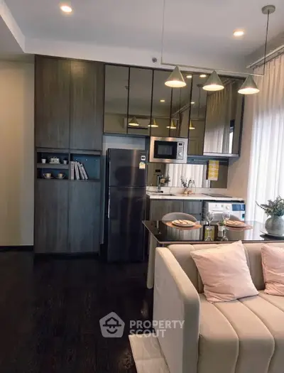 Modern living room with open kitchen, sleek appliances, and stylish decor in a cozy apartment.