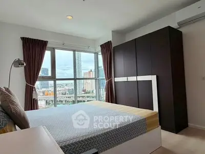 Modern bedroom with large windows offering city views, featuring a stylish wardrobe and cozy bed.