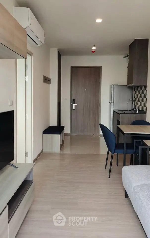 Modern apartment interior with open layout, featuring a cozy living area and compact kitchen.