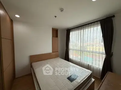 Spacious bedroom with large window offering city views, featuring a comfortable bed and modern design.