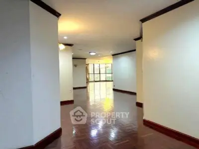 Spacious living room with polished wooden floors and large windows for natural light.