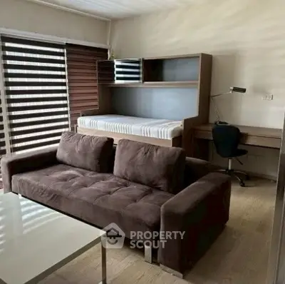 Modern living room with brown sofa, desk, and bed in compact layout.