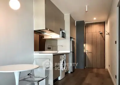 Modern studio apartment with sleek kitchen and integrated appliances, featuring a washing machine and stylish decor.