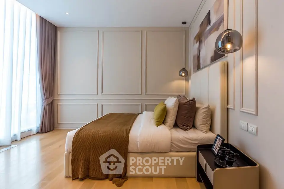 Luxurious bedroom with elegant decor and natural light, featuring modern pendant lights and plush bedding.