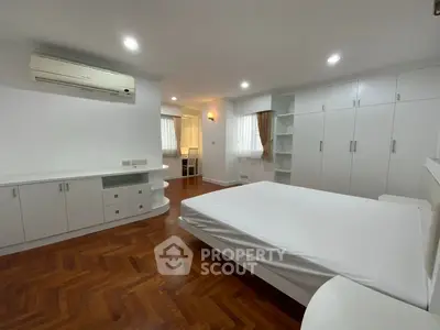 Spacious bedroom with modern white furniture and wooden flooring