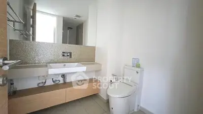 Modern bathroom with sleek fixtures and minimalist design, featuring a large mirror and stylish vanity.