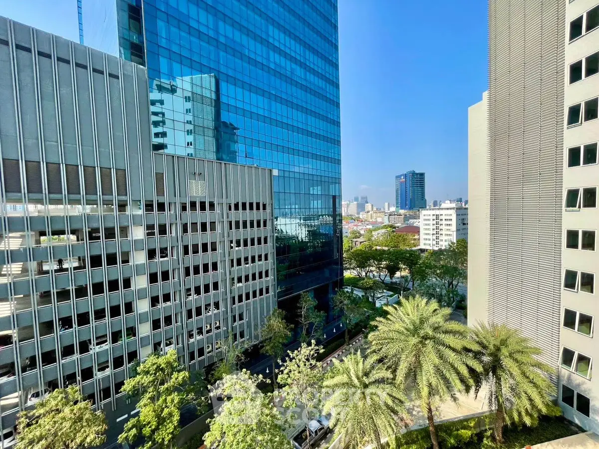 Stunning cityscape view from high-rise building with lush greenery and modern architecture.