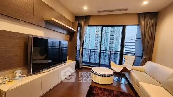 Modern living room with large TV and city view from balcony.