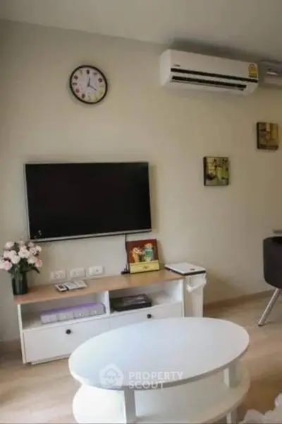 Cozy living room with modern decor, wall-mounted TV, and air conditioning unit.