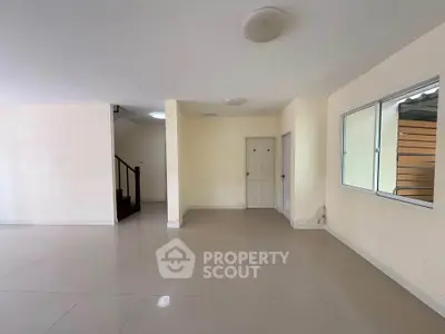 Spacious unfurnished room with tiled flooring and staircase, ideal for customization.
