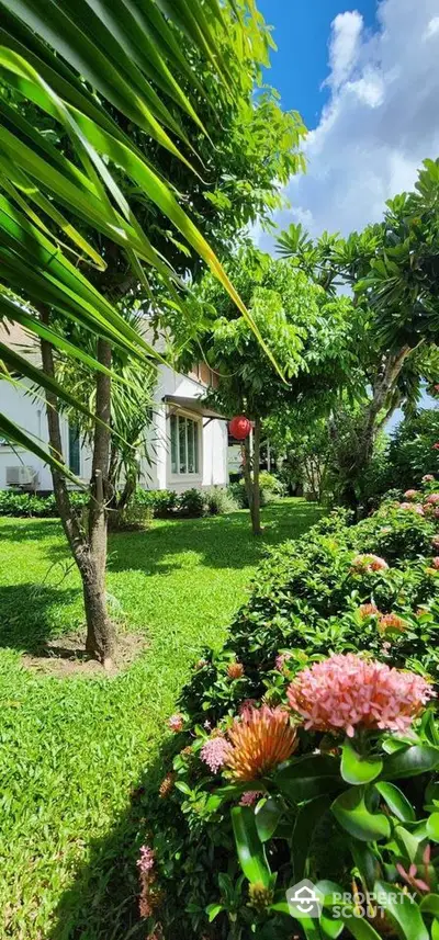 Lush garden view with vibrant flowers and trees surrounding a charming house exterior.