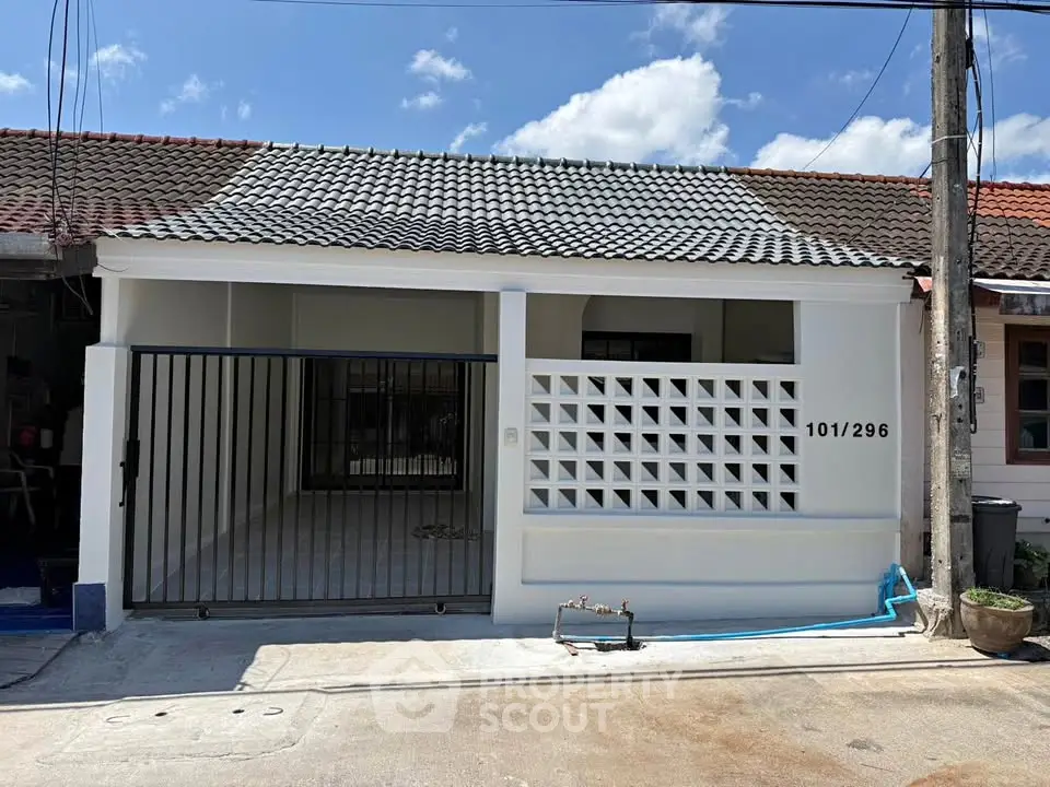 Charming single-story home with tiled roof and gated entrance, perfect for cozy living in a serene neighborhood.