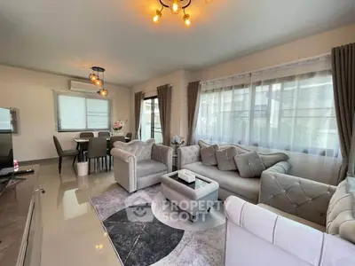 Elegant living room with plush sofas and modern dining area, featuring large windows and stylish lighting.