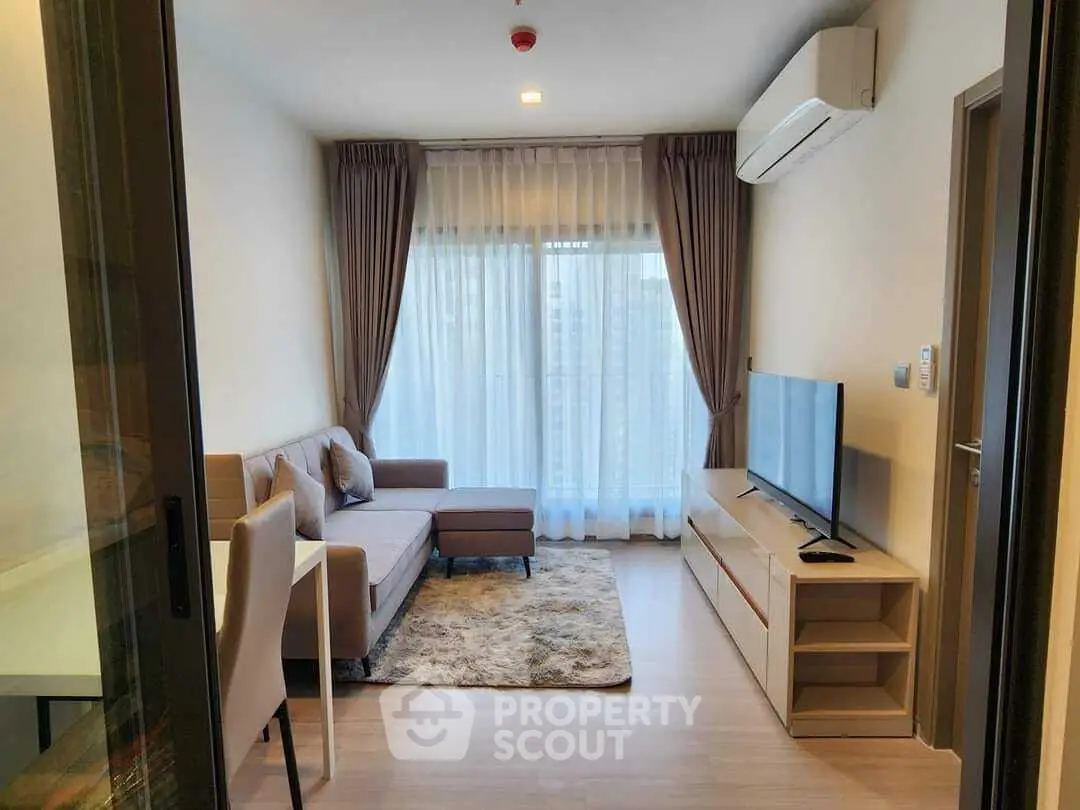 Modern living room with cozy sofa, large window, and sleek TV setup in a stylish apartment.