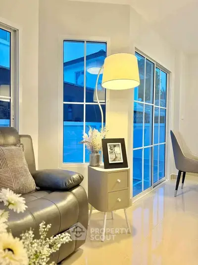 Modern living room with sleek leather sofa and elegant decor, featuring large windows for natural light.