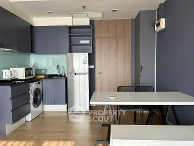 Modern kitchen with sleek cabinetry, washing machine, and dining area in a stylish apartment.