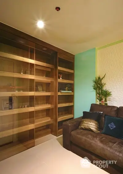 Cozy living room corner with a large, plush leather sofa and a built-in wooden display cabinet, accented by soft lighting and warm tones.