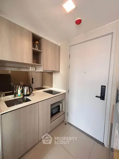 Modern compact kitchen with sleek cabinetry and built-in appliances in a stylish apartment.