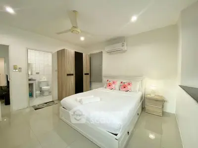 Modern bedroom with ensuite bathroom, featuring sleek design and air conditioning.