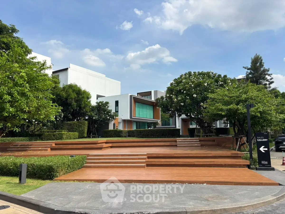 Modern architectural exterior with lush greenery and wooden deck in a serene residential setting.