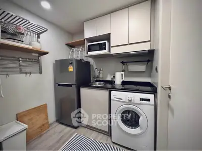 Compact modern kitchen with washing machine and microwave in cozy apartment.