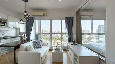 Modern open-plan living room with city view, featuring sleek furniture and large windows for natural light.
