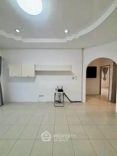 Spacious living room with modern ceiling design and tiled flooring, perfect for customization.
